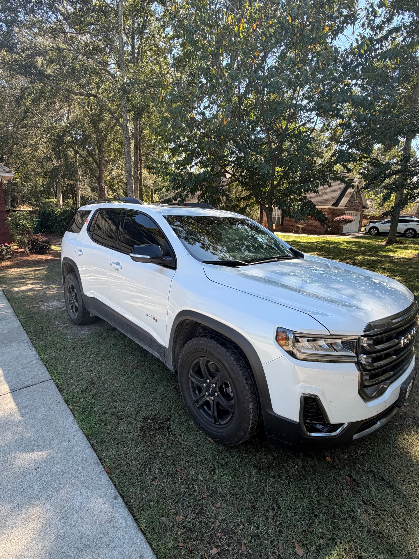 White GMC SUV with dark tinted windows parked beside a driveway