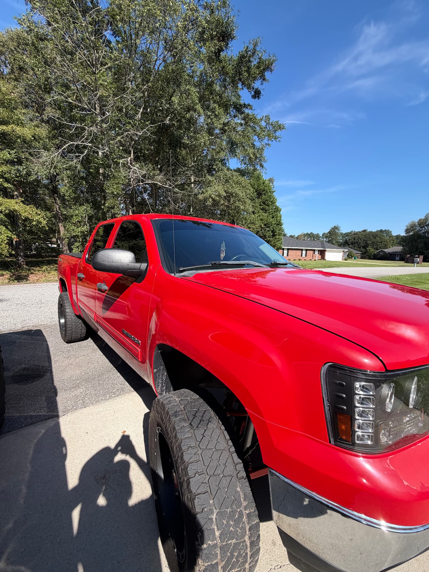Close view of a red GMC pickup showing its dark windshield and side windows