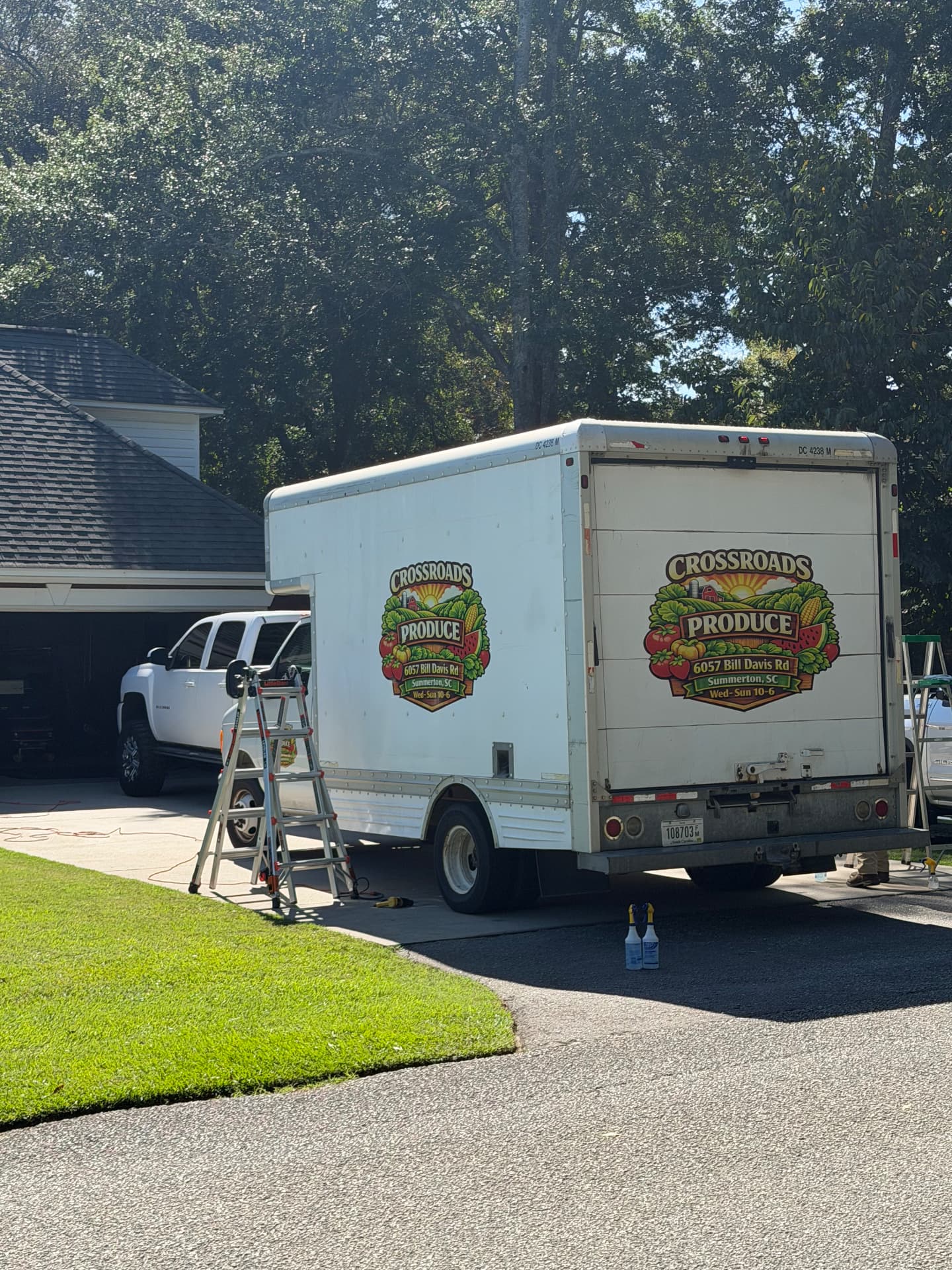 Rear view of a Crossroads Produce box truck parked beside tinting equipment