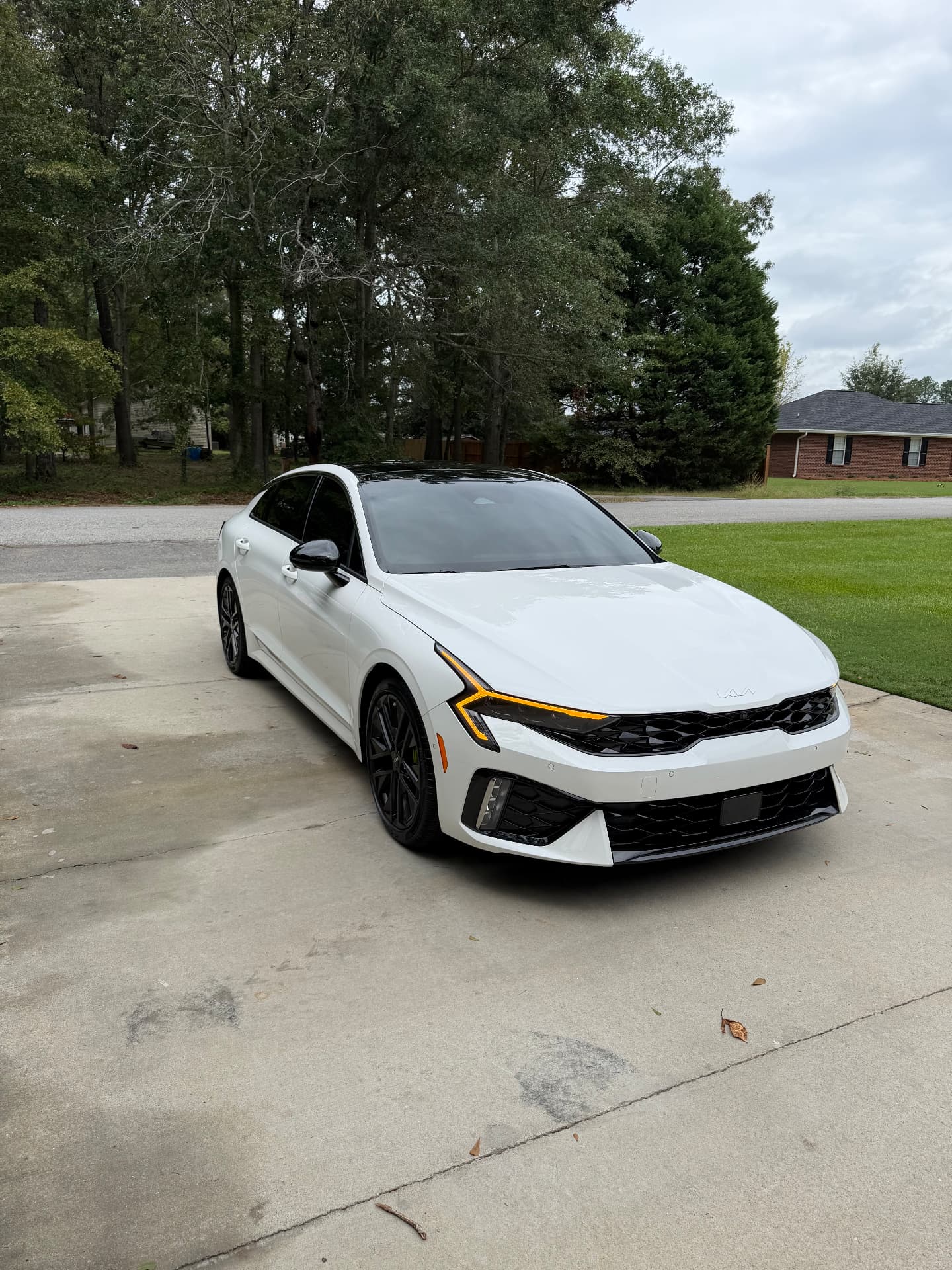 White Kia sedan showing its windshield and dark side windows