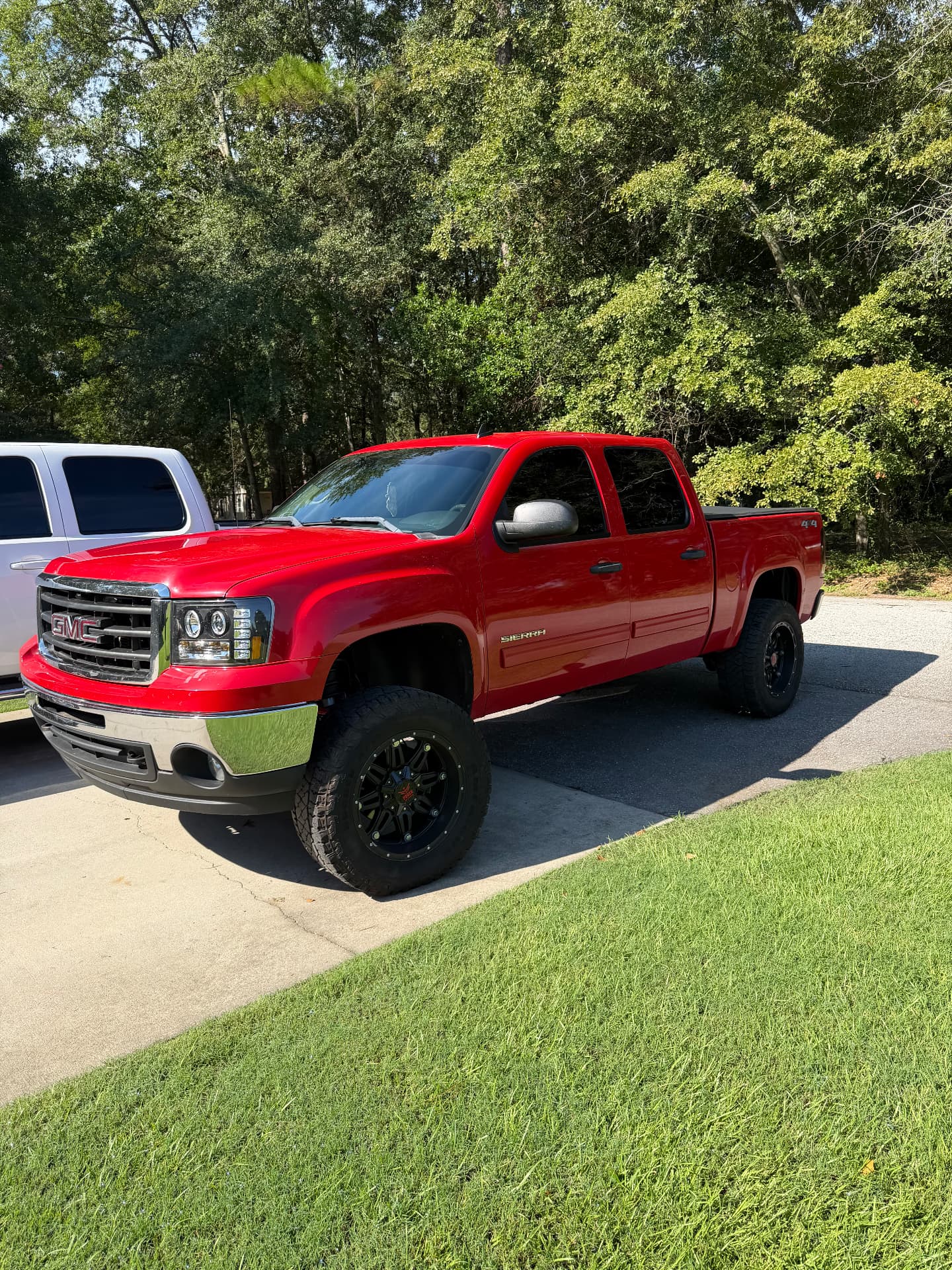 Red GMC Sierra pickup with tinted windows parked on a driveway